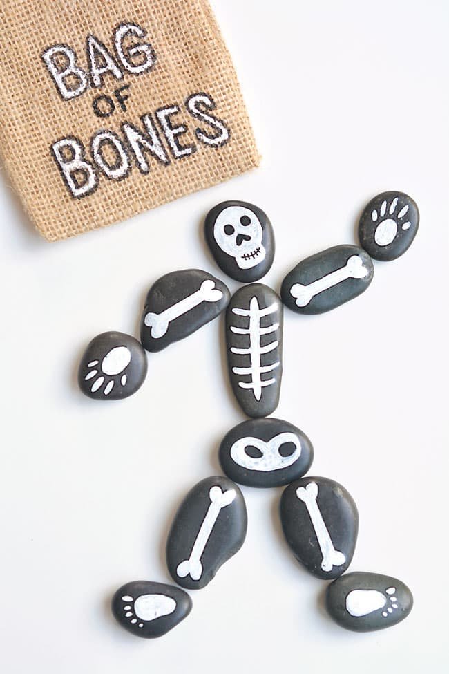 Bag of bones Halloween painted rocks beside a labeled burlap bag