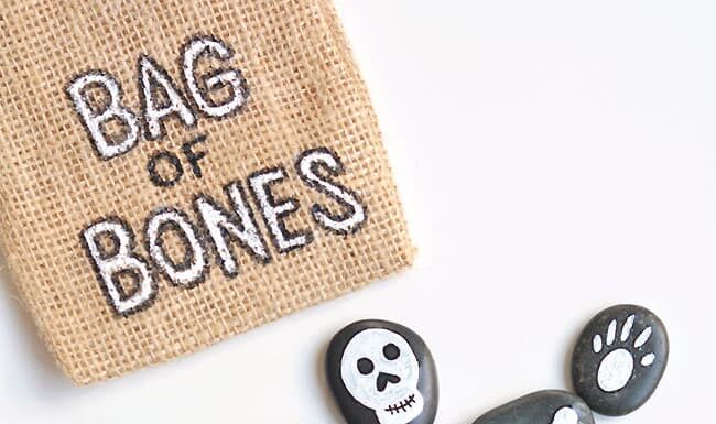 DIY Bag of Bones Halloween Painted Rocks Bag of bones Halloween painted rocks beside a labeled burlap bag