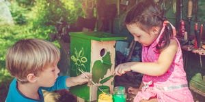 little boy and girl building and painting birdhouse outdoors in summer