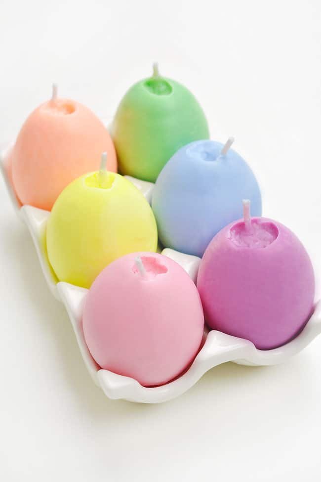 Six different colours of homemade candles shaped like Easter eggs