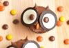 How to Make Easy Owl Cupcakes for Halloween Owl cupcakes on a wooden background surrounded by reese's pieces