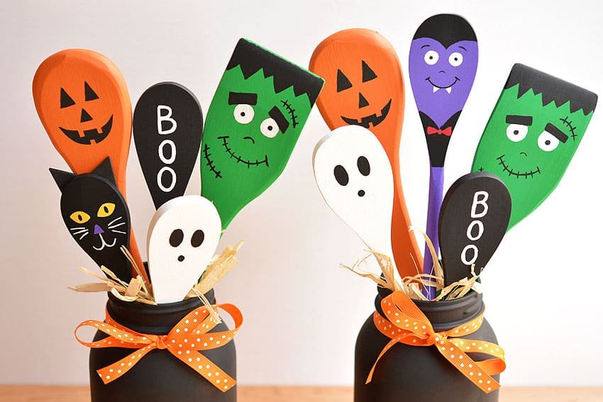 Wooden spoons painted as a jack-o-lantern, black cat, ghost, Frankenstein, and vampire