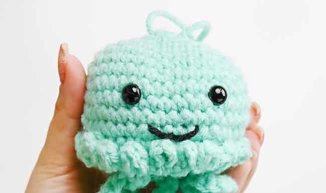 How to Crochet a Jellyfish: Step-by-Step Guide Holding a seafoam green crochet jellyfish
