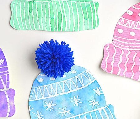 Kids Winter Hat Art Project With DIY Pom Poms This winter hat art project for kids is such a fun winter craft idea! Use the free printable winter hat template to have a fun day of crafting at home or in the classroom! This process art idea lets you experiment with creating texture in watercolor and shows the magic of painting over crayon with watercolour paint! There's even instructions for making a DIY yarn pom pom!