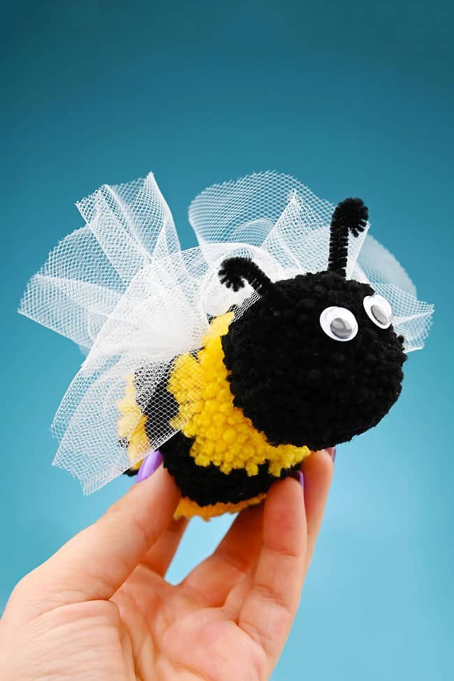 Holding a soft and fuzzy DIY pom pom bee craft