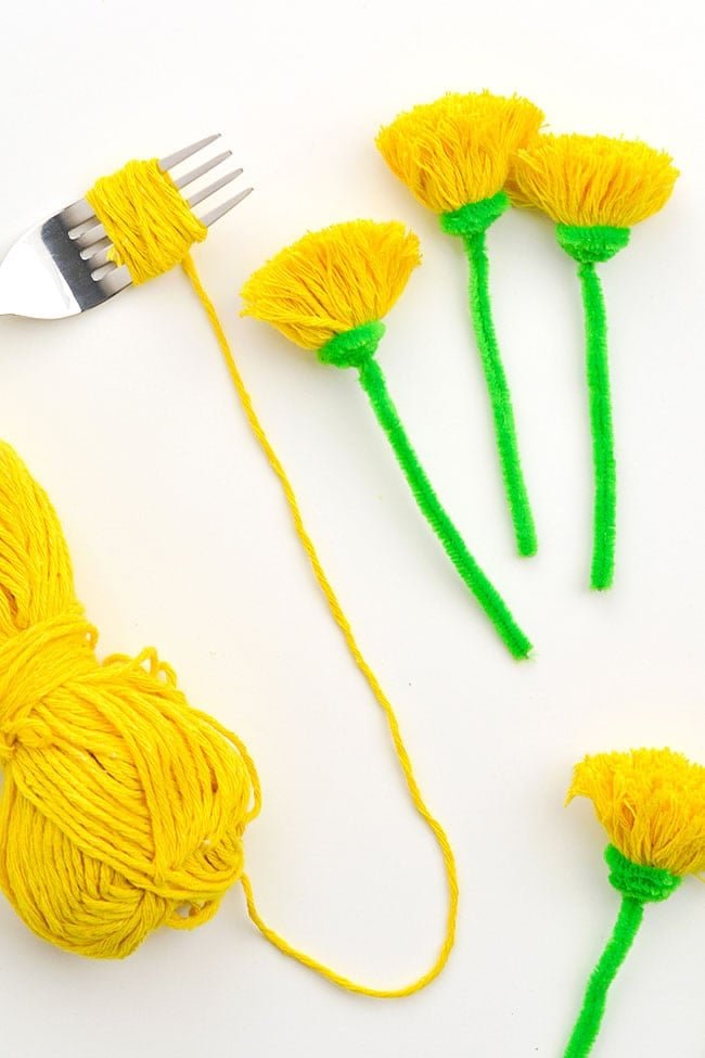 Use a fork to make a pom pom dandelion from yarn and a pipe cleaner