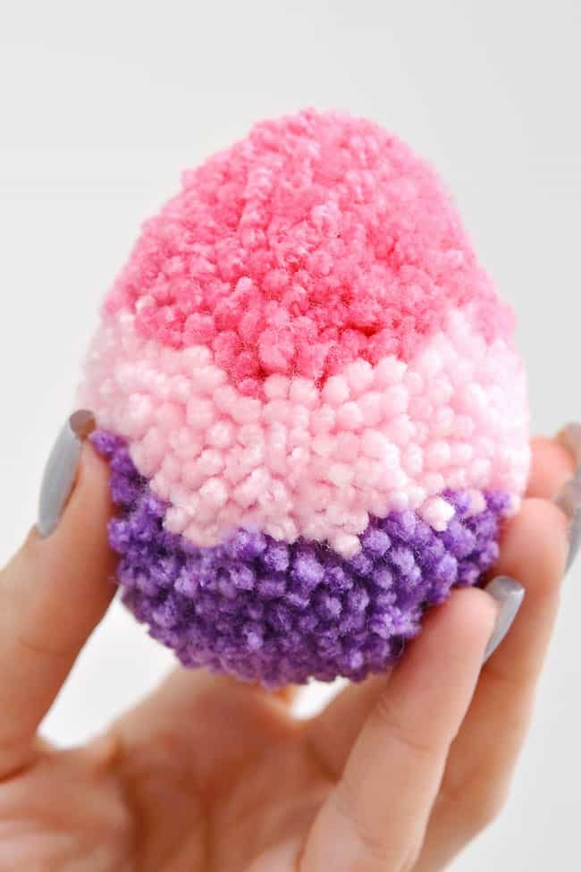 Holding a fluffy pink and purple pom pom Easter egg