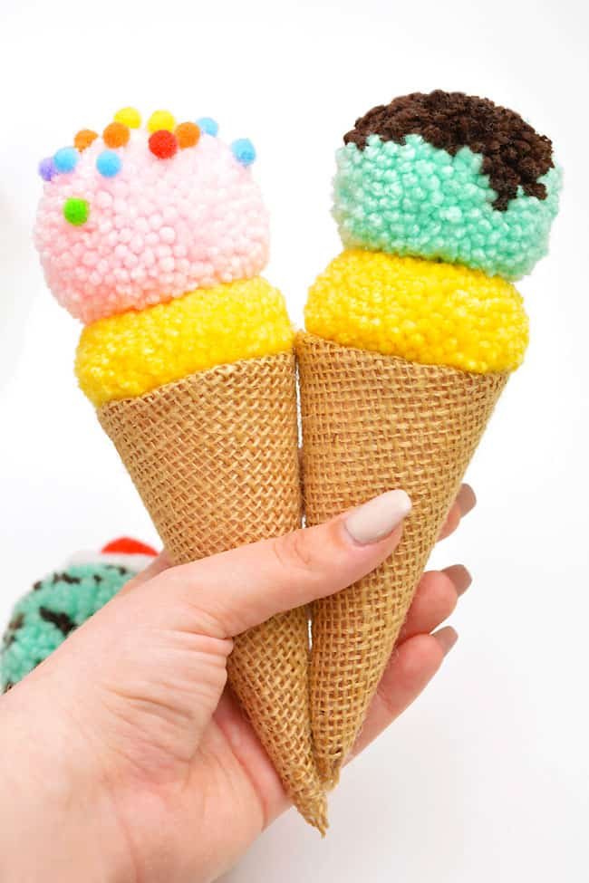 Holding two colourful pom pom ice cream crafts