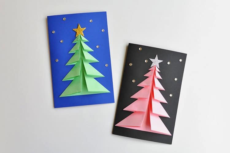 A green 3D Christmas tree on a blue card with gold stars and a pink 3D Christmas tree on a black card with silver stars