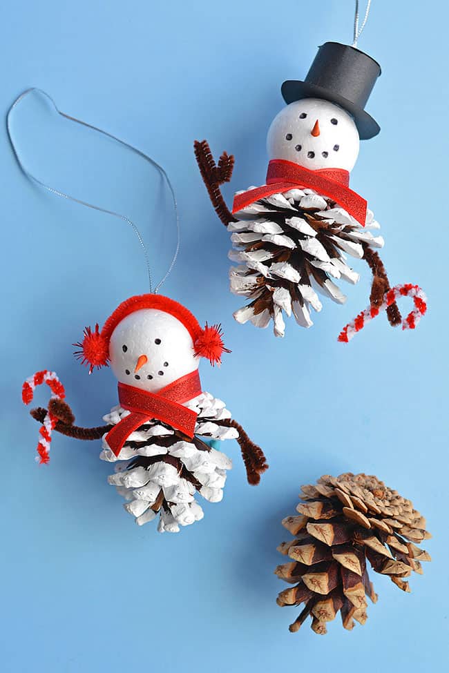 These pinecone snowman ornaments are so FUN and look super cute hanging from the tree! Such a fun Christmas craft for kids of all ages! Using dollar store supplies you can transform a regular old pinecone into a little bundled-up snowman complete with a top hat, scarf and earmuffs! It's a great homemade Christmas ornament you can pull out year after year. Or you can leave it up all winter long as a frosty decoration!