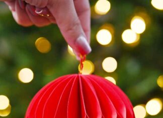 How to Make a Honeycomb Ornament DIY paper honeycomb ornament in front of a Christmas tree