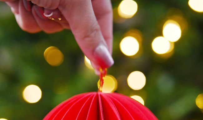 How to Make a Honeycomb Ornament DIY paper honeycomb ornament in front of a Christmas tree