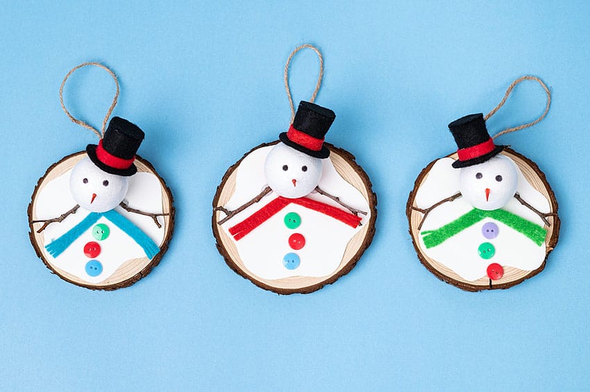 Three melted snowmen ornaments lined up on a blue background