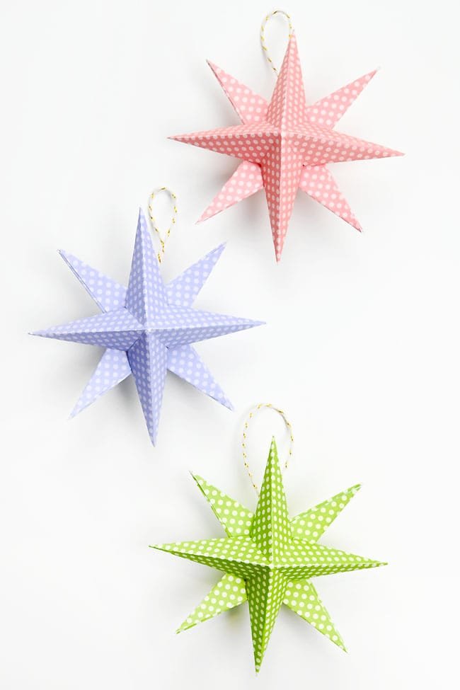 Pink, blue, and green paper star ornaments on a white background