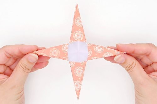 Fingers holding paper star by 2 points