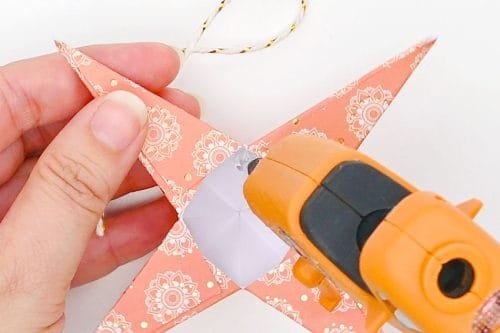 Glue gun adding hot glue to paper star