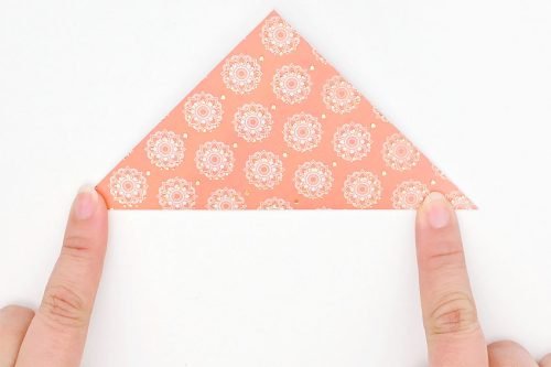 Decorative paper folded in a triangle with fingers holding down bottom 2 corners