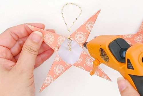 Glue gun adding hot glue to inner corner of paper star