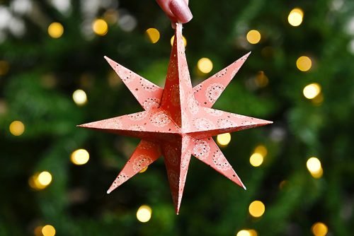 Paper star ornament in front of lighted Christmas tree