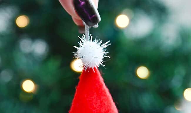 How to Make a Pinecone Gnome Holding a DIY pinecone gnome ornament in front of the Christmas tree