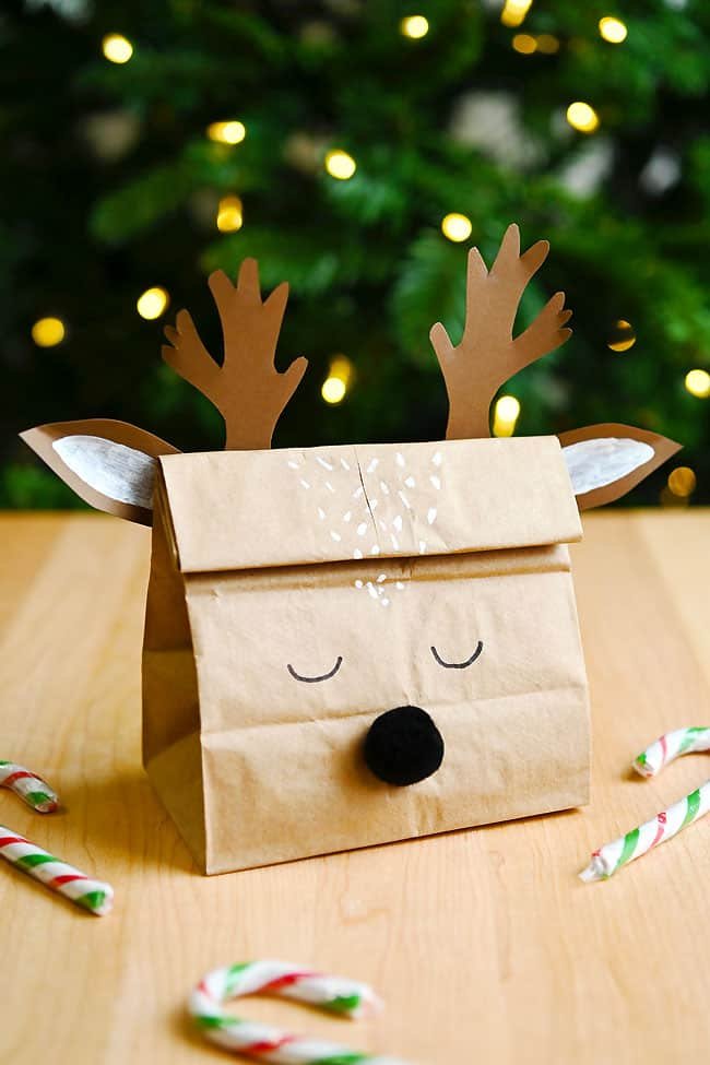 Cute reindeer gift bag craft in front of a Christmas tree