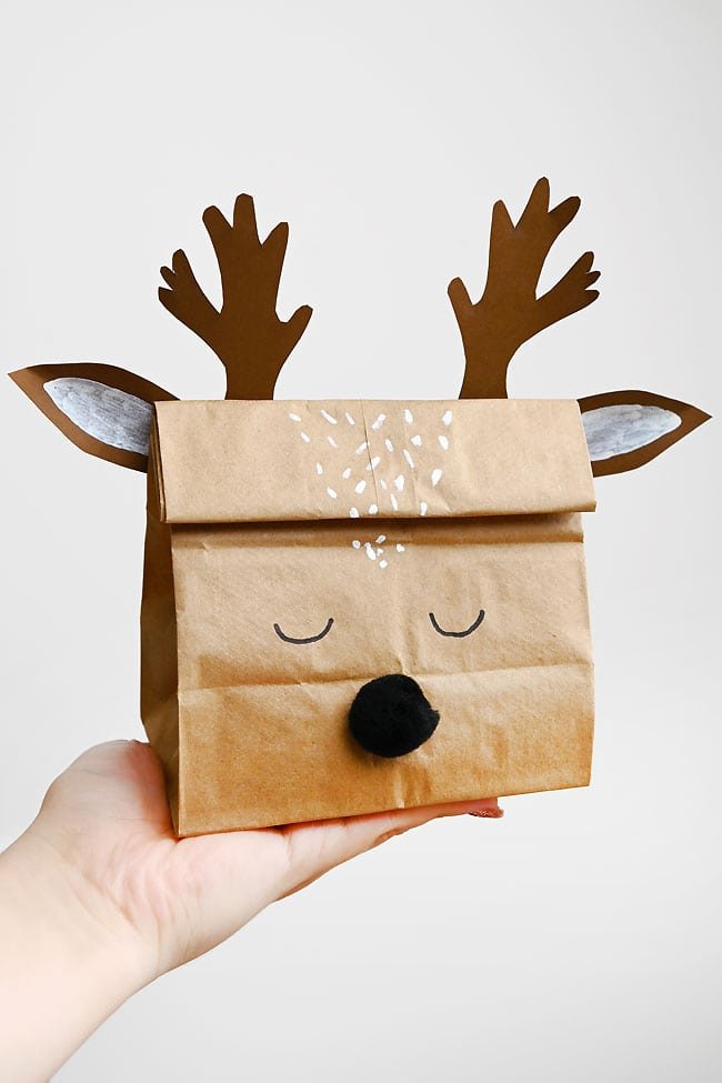 Holding a reindeer gift bag filled with Christmas candy