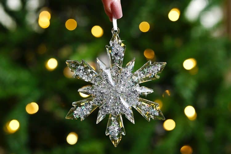 Snowflake ornament made of resin and glitter in front of lighted Christmas tree