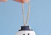 How to Make Seashell Snowman Ornaments Seashell snowman ornament hanging in front of a blue background