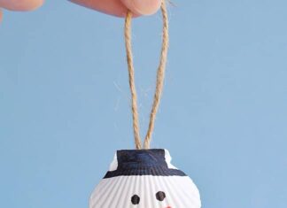 How to Make Seashell Snowman Ornaments Seashell snowman ornament hanging in front of a blue background