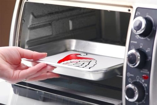 Pan with shrink plastic ornament entering oven