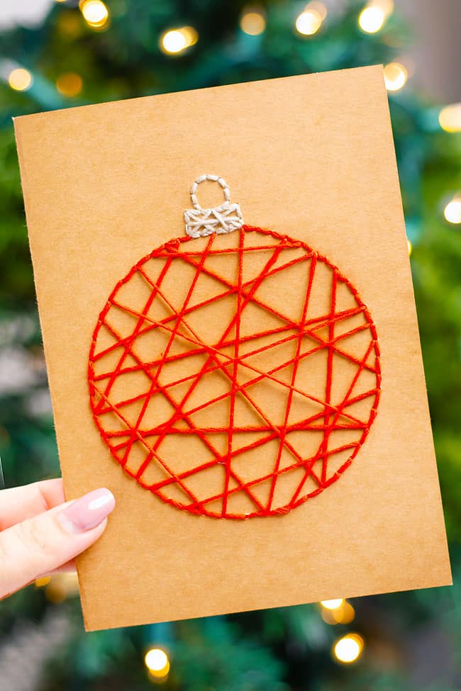 String art Christmas card held in front of a Christmas tree